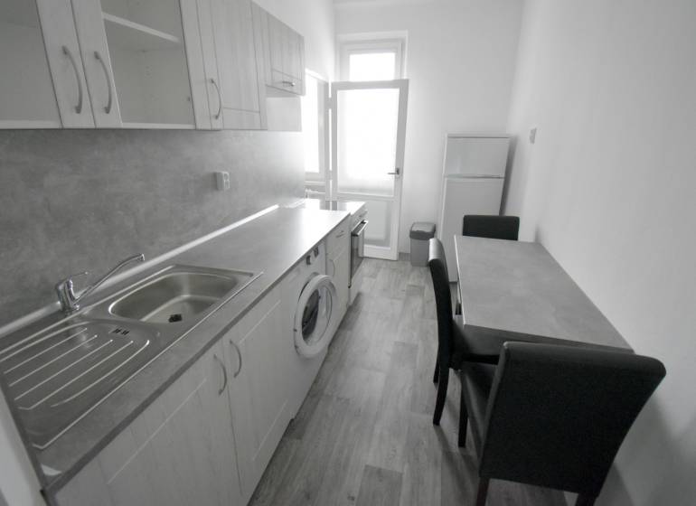 Pekný 3i byt, 3 x NEPRIECH.IZBA, BALKÓN, Radarová ulica, Ostredky - Kuchyňa v 3-izbovom byte s podlahou s dreveným dekorom, umývadlom a jedálenským stolom.