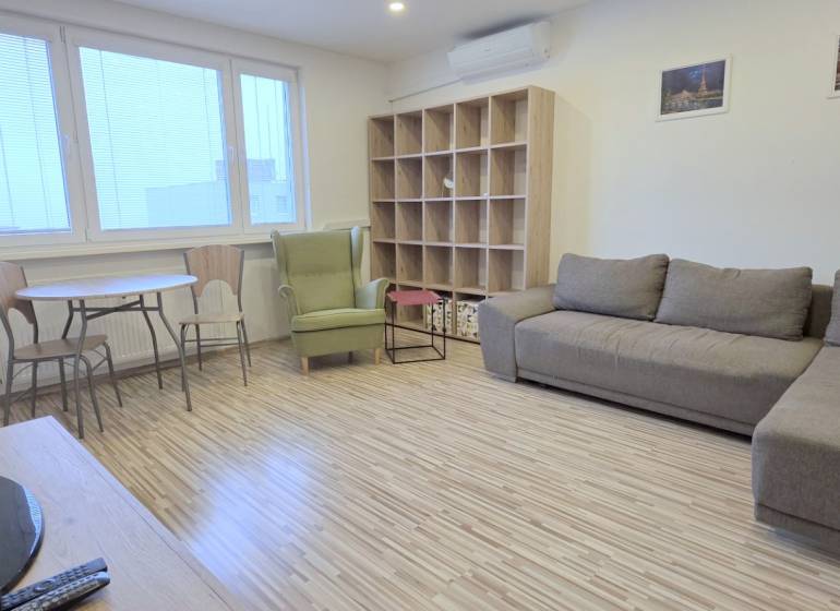 MODERNÝ 2i byt, REKONŠTRUKCIA, KLÍMA, MOZARTOVA ulica, Horský park - Obývacia izba v 2-izbovom byte s podlahou s dreveným dekorom a pohodlnou sedačkou.