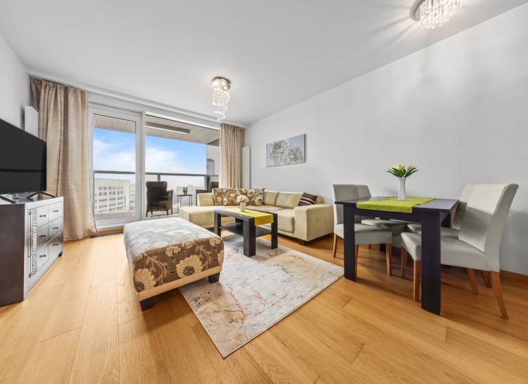 KRÁSNY 2i byt, KLÍMA, LOGGIA,VÝHĽAD,PANORAMA CITY, Landererova ulica - Obývacia izba 2-izbového bytu s podlahou s dreveným dekorom, sedačkou a jedálenským stolom.