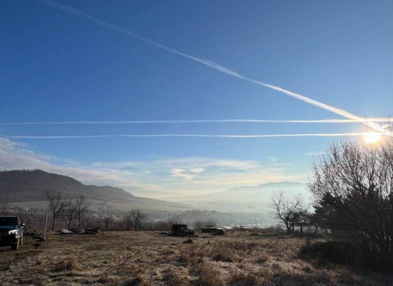 KH-1051, Pozemok, záhrada, Prešov, Fintice - Krajina v Záhradách Fintíc s kopcami, modrou oblohou a slnečnými lúčmi.