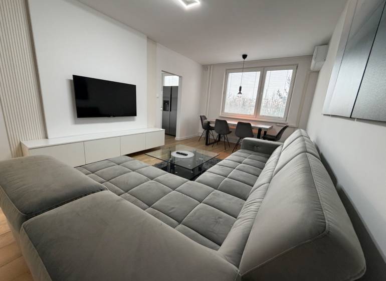 3 izbový byt s balkónom Topoľčany / PRENAJOM  - Obývací priestor v 3-izbovom byte s pohovkou, TV a jedálenským stolom, podlaha s dreveným dekorom.