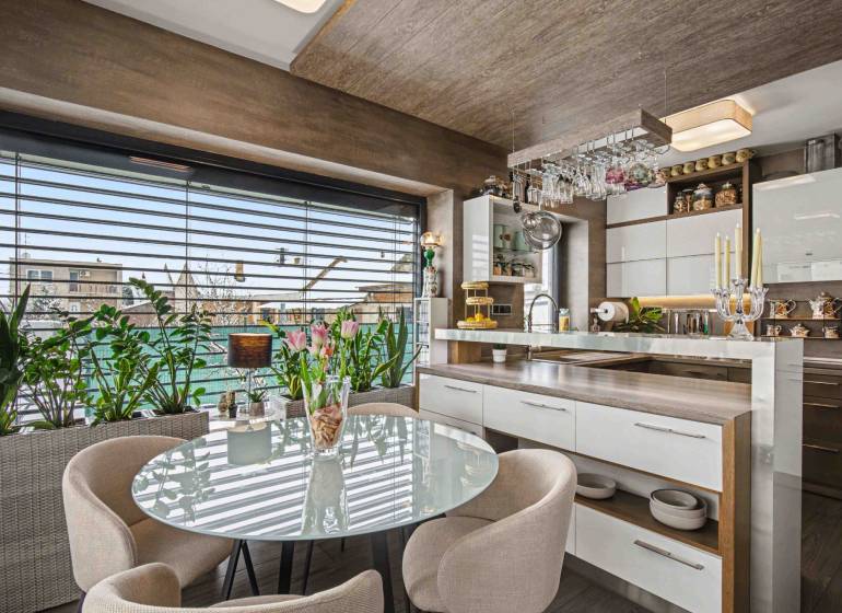 Ideálny dom pre rodinu, Blatné, okr. Senec - Jedálenský kút v rodinnom dome s preskleným stolom, rastlinami a kuchynským príslušenstvom.