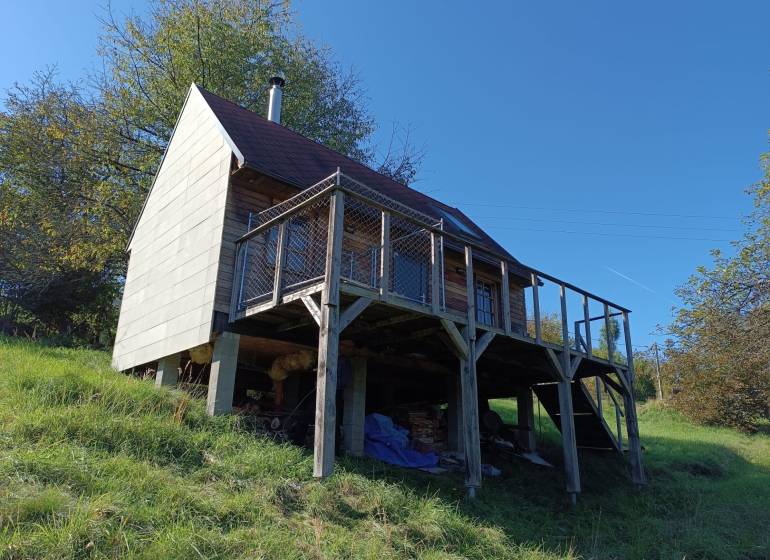 Na predaj záhradná chatka - Chata na ulici Na Gremenici v Žarnovici s drevenou terasou a podpornými stĺpmi.