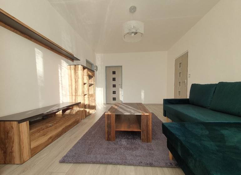 KH-1052, 3 izbový byt, Košice – Staré Mesto, širšie centrum, Kuzmányho - Obývacia izba v 3-izbovom byte s pohovkou, skriňou a stolíkom na podlahe s dreveným dekorom.