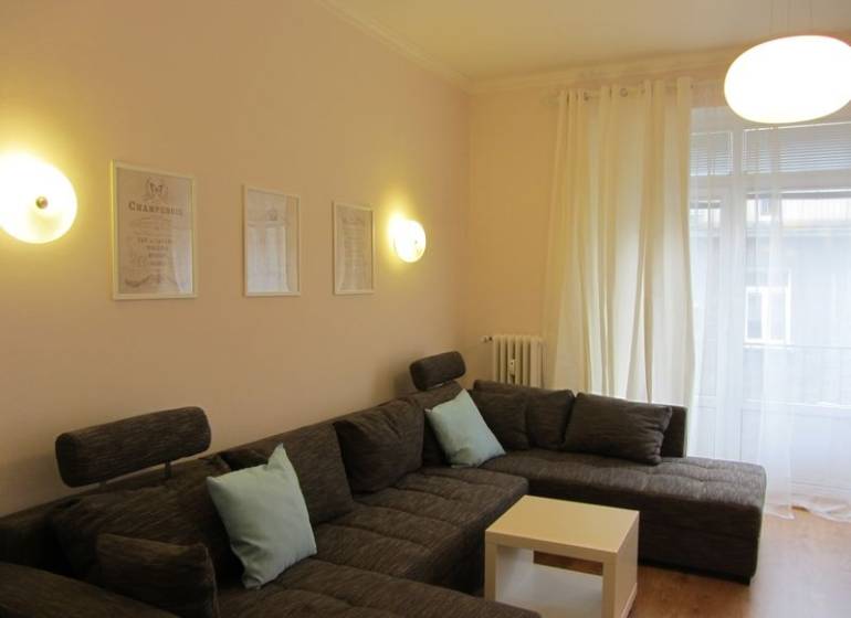 4-izb.byt v centre mesta, Obchodná ul., BA I - Staré Mesto, 2 x balkón - Pohodlná sivá sedacia súprava v obývačke 4-izbového bytu s bielymi záclonami.