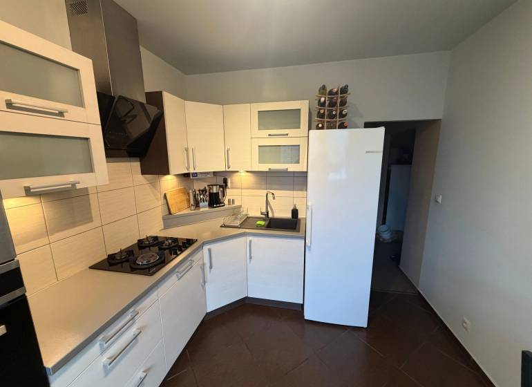 4-izb. byt, Wolkrova, Petržalka, 7.p./8 - Kuchyňa v 4-izbovom byte s bielymi skrinkami a tmavou podlahou s dreveným dekorom.