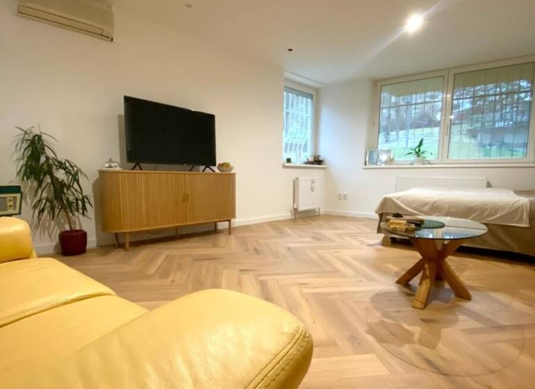 4-izb. byt, Cabanova ul., Dúbravka so samostatným vstupom - Obývacia izba so žltou sedačkou, TV a dreveným stolom v 4-izbovom byte na ulici Cabanova.