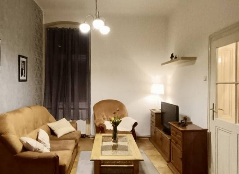 – PRENAJOM – 3 IZBOVÝ BYT – STARE MESTO  - Obývačka v 3-izbovom byte s podlahou s dreveným dekorom, útulné sedenie a osvetlenie.