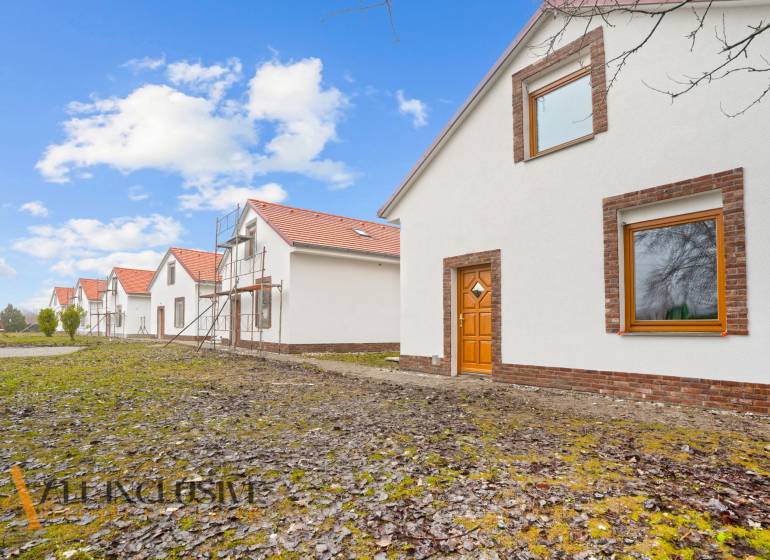 NA PREDAJ 4-IZBOVÉ RD – REZIDENČNÝ PROJEKT, GABČÍKOVO - Rodinné domy v Gabčíkove s bielou fasádou, pred nimi zelený trávnik a modrá obloha.