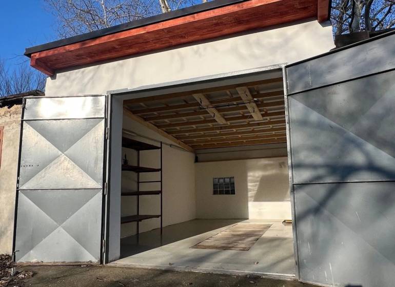 Zrekonštruovaná veľká garáž na ul. Agátova, Dúbravka s pozemkom - Otvretá garáž na Agátovej v Bratislave - Dúbravke s jednoduchým interiérom a regálom.