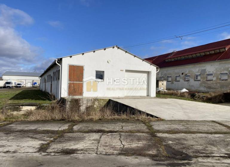 Na prenájom skladová hala, obec Rybky, okr. Senica - Exteriér skladov a hál v Rybkách s bielou fasádou a drevenými dverami.