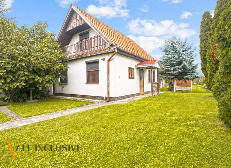 NA PREDAJ 2-IZBOVÝ RODINNÝ DOM S PODKROVÍM, BODÍKY - Rodinný dom v Bodíkoch s trávnatým pozemkom a stromami v pozadí.