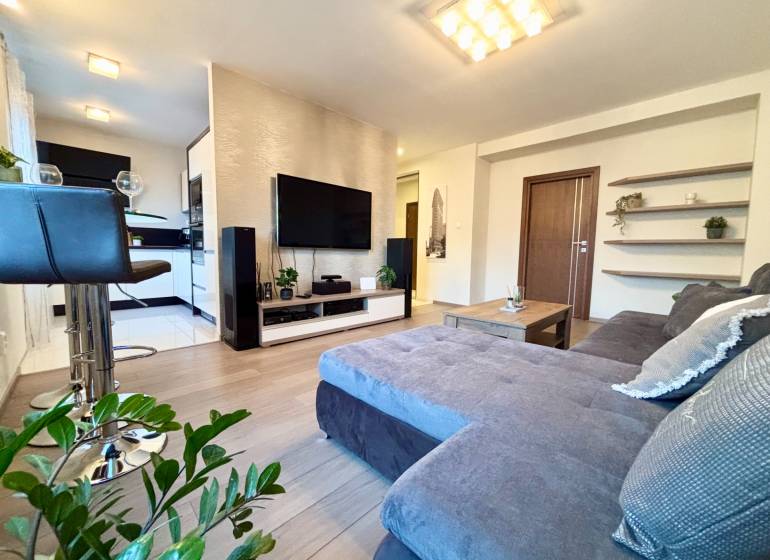 Štýlový, zariadený 2- izbový byt s balkónom pri stanici!!! - Obývacia izba v 2-izbovom byte s pohodlnou sedačkou a podlahou s dreveným dekorom.