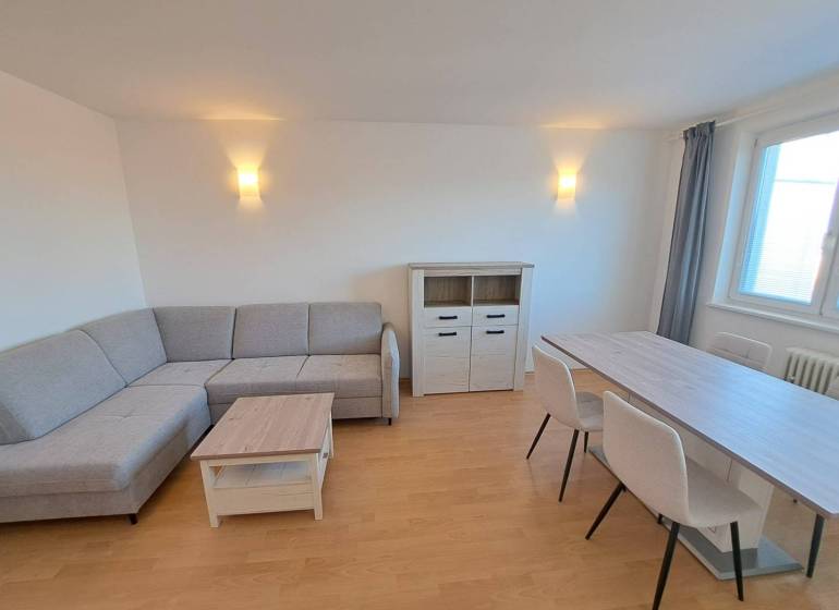 Prenájom pekného a priestranného 4-izbového bytu vo Svite - Obývacia izba v 4-izbovom byte s rohovou sedačkou a jedálenským stolom.