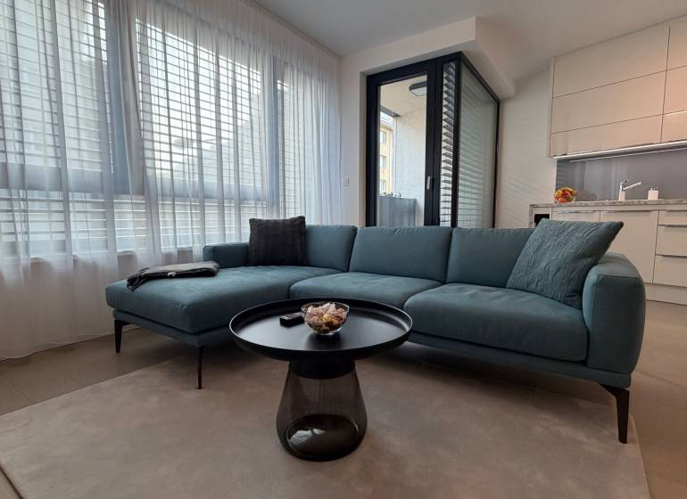 Exk. prenájom lux. 2 iz bytu Rezidencia Blumental - Obývačka s pohovkou, stolíkom a kuchynským kútom v 2-izbovom byte.