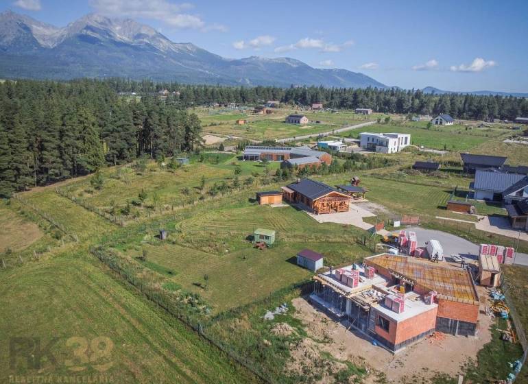 Jedinečný stavebný pozemok v krásnej lokalite Tatranské Smaragdy - Pozemky - bývanie v Mlynici s výhľadom na hory a rozostavanými domami v prírode.