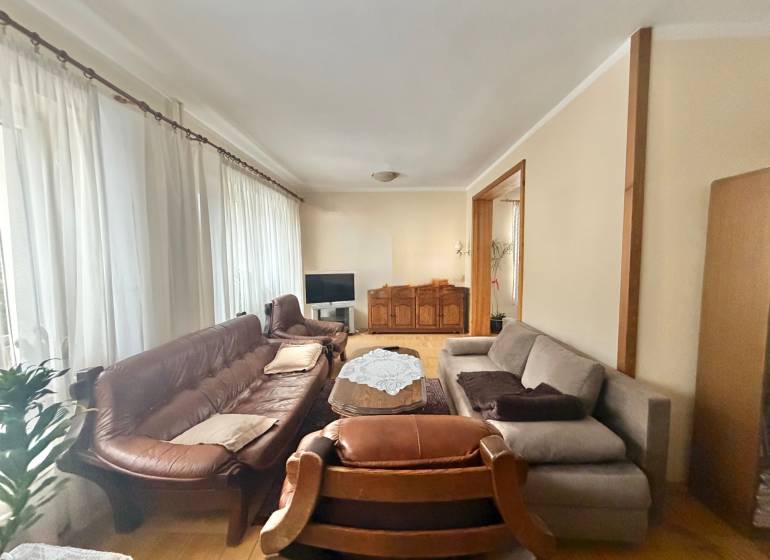 Prenájom exkluzívneho domu v Čadci- Čadečke - Obývačka v rodinnom dome s podlahou s dreveným dekorom, sedačkou a záclonami.