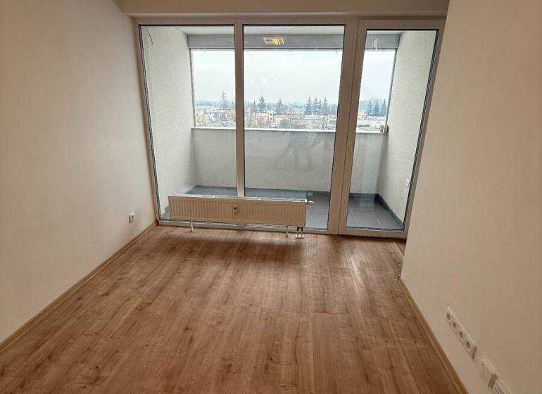 Na predaj 1,5-izbový byt v novostavbe GREENSIDE Trebišov - Obývacia izba v 1-izbovom byte s podlahou s dreveným dekorom a veľkými oknami.