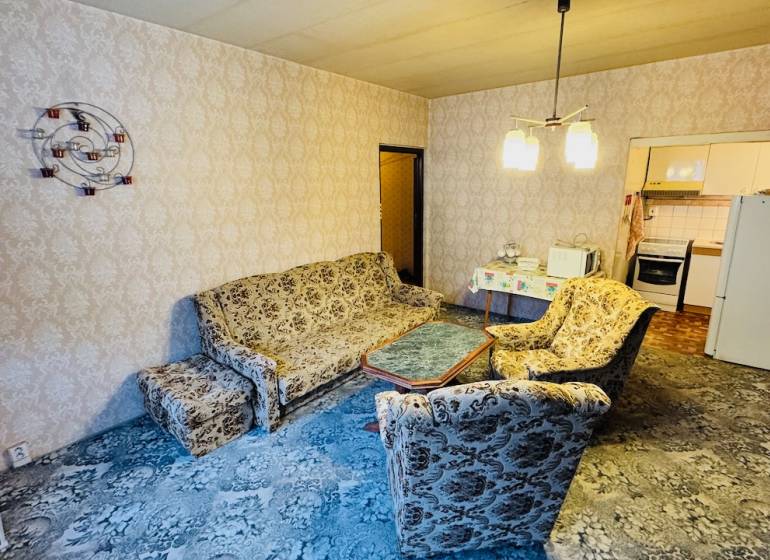 Na predaj 2 i byt v Partizánskom - Šípok - Obývacia izba s retro sedacou súpravou, vzorovaný koberec, vstup do kuchyne v 2-izbovom byte.