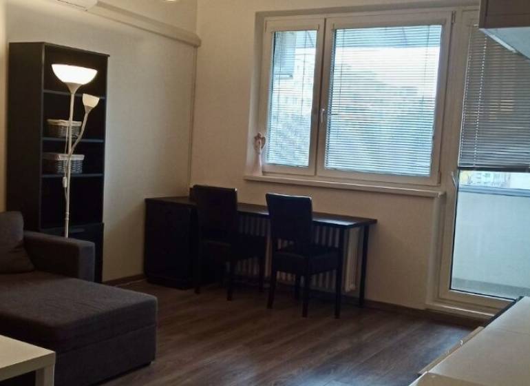 Prenájom 2-izbový byt na začiatku Petržalky - Obývacia izba v 2-izbovom byte s rohovou sedačkou a podlahou s dreveným dekorom.