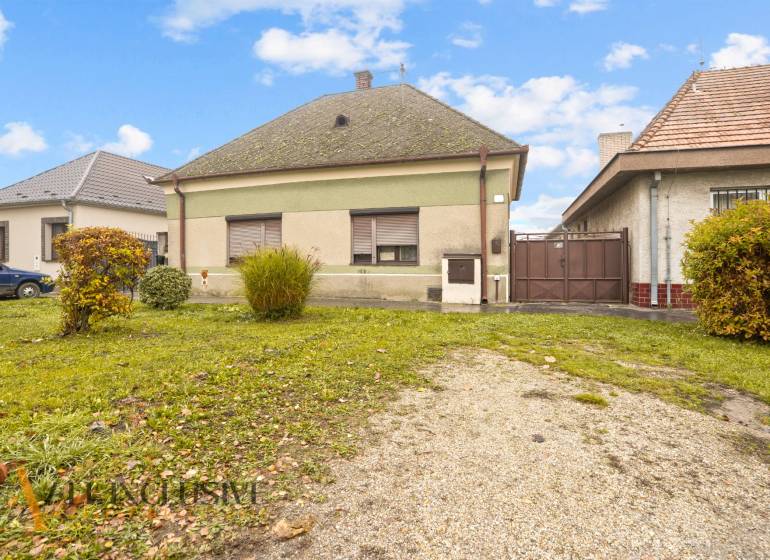 NA PREDAJ 4-IZBOVÝ RODINNÝ DOM V OBCI MOSTOVÁ - Rodinný dom v Mostovej so zelenou fasádou a záhradou s kríkmi.