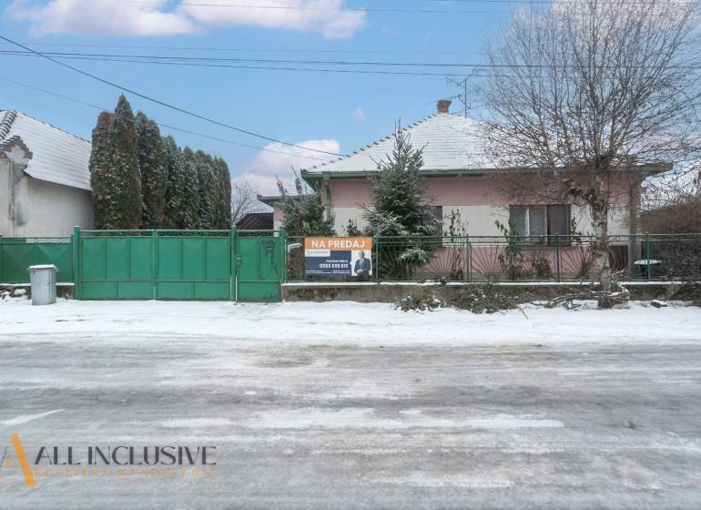 Na predaj 4-izbový rodinný dom, Gabčíkovo - Rodinný dom v Gabčíkove s predajným nápisom a zasneženým okolím.