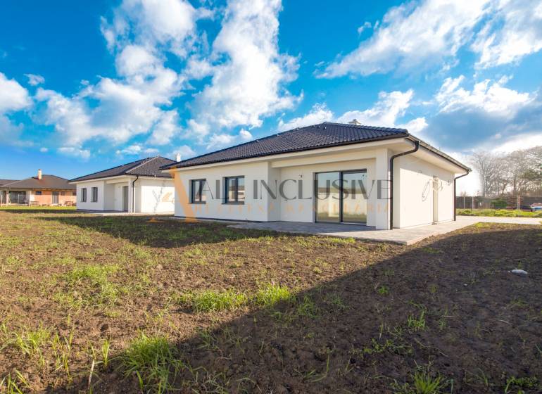 NA PREDAJ 4 IZBOVÝ RODINNÝ DOM-NOVOSTAVBA, KRÁĽOV BROD - Rodinný dom s bielou fasádou a tmavou strechou uprostred zelenej lúky.