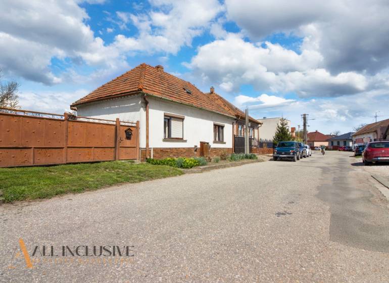 NA PREDAJ RODINNÝ DOM NA 9,5 ÁROVOM POZEMKU, OHRADY - Rodinný dom na ulici Ohrady v Dunajskej Strede s tradičnou strechou a bránou.