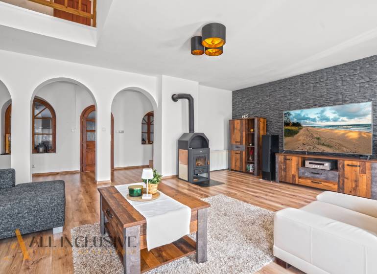 REZERVOVANÉ ZREKONŠTR. 6 IZBOVÝ RODINNÝ DOM, KOŠÚTY - Obývacia izba v rodinnom dome s krbom, oblúkovými dverami a podlahou s dreveným dekorom.