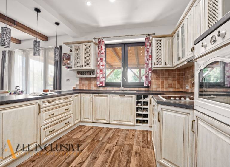 NA PREDAJ 4-IZB NOVOSTAVBA S TROJGARÁŽOU, PIN. KRAČANY - Kuchyňa v rodinnom dome s dreveným dekorom a béžovými skrinkami, svetlé a útulné.