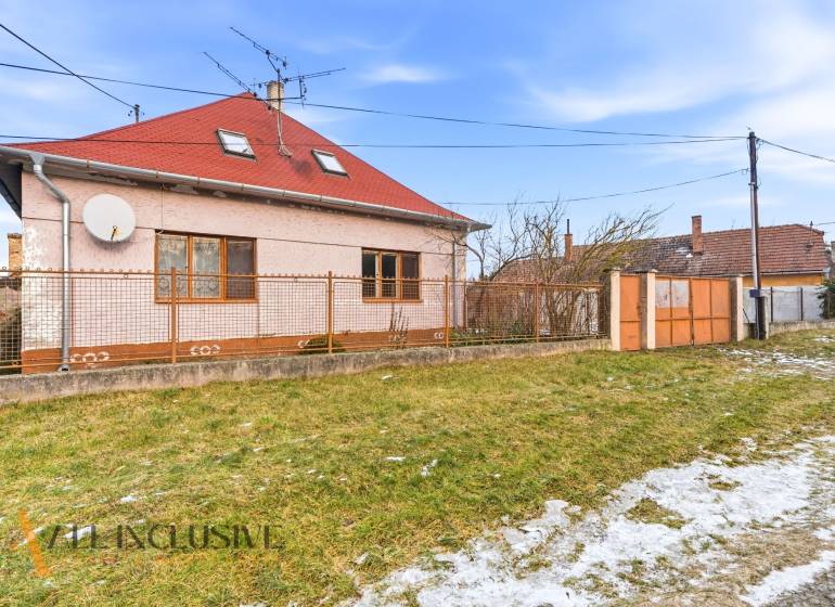 Na predaj 3-izbový rodinný dom, Dobrohošť - Rodinný dom v Dobrohošti s červenou strechou a oploteným pozemkom. Trávnatá plocha so snehom.