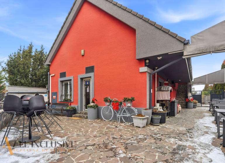 Na prenájom podnikateľské priestory, Senec - Exteriér hotela či penziónu v Senci so stoličkami a bicyklom pred oranžovou budovou.