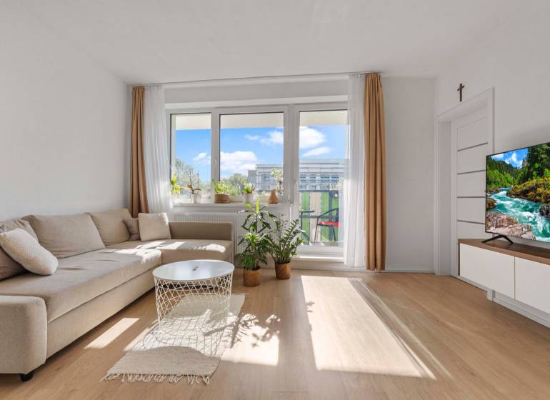 | Krásny a moderný 2-izbový byt | 51,50m² | - Obývacia izba v 2-izbovom byte s pohovkou a balkónovými dverami. Podlaha s dreveným dekorom.