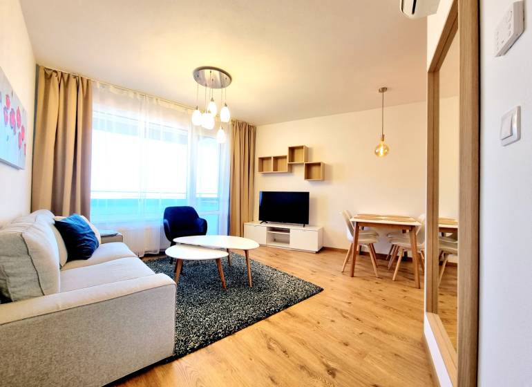 Posledný investičný krásny 2-izbový byt | 55 m² | RÍNOK RAČA - Obývačka v 2-izbovom byte s pohodlným nábytkom a podlahou s dreveným dekorom.