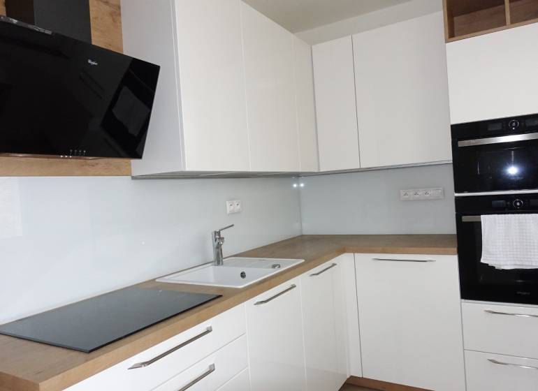 PRENÁJOM –  1 izba (príp. 2 izby) v 3-izb. byte, Gwerkovej ul., BA V - Kuchyňa s bielymi skrinkami a spotrebičmi, doplnená podlahou s dreveným dekorom v 3-izbovom byte.