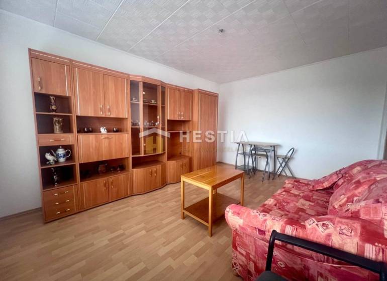 TOP 3 izbový byt v Moravskom Lieskovom s garážou a predzáhradkou - Obývacia izba v 3-izbovom byte s červenou sedačkou a drevenou obývacou stenou.