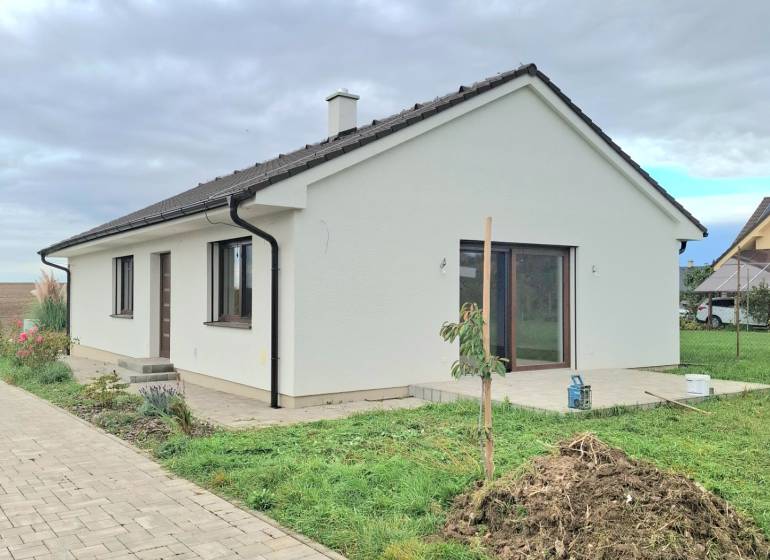 | 4 izbový rodinný dom s krbom a terasov | Slnečná | Ružindol - Rodinný dom na Slnečnej v Ružindole s bielou fasádou a zámkovou dlažbou.