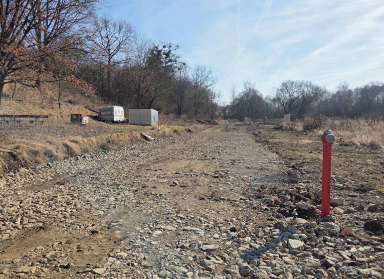 NA PREDAJ STAVEBNÝ POZEMOK  V DOSAHU MHD PREŠOV - HANISKA - Pozemky - bývanie v Haniske, kamenistá cesta medzi stromami a kontajner.