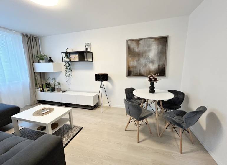 NA PREDAJ ŠTÝLOVÝ 2- IZBOVÝ BYT, 50m2, SÍDLISKO 2, PREŠOV - Interiér 2-izbového bytu so stolom, stoličkami a dekoráciami, podlaha s dreveným dekorom.