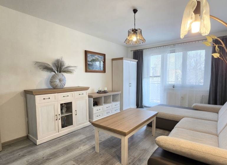 Moderný 2-izbový byt po rekonštrukcii v srdci Zlatého potoka - Zvolen - Obývacia izba v 2-izbovom byte s podlahou s dreveným dekorom, sedačkou a bielym nábytkom.