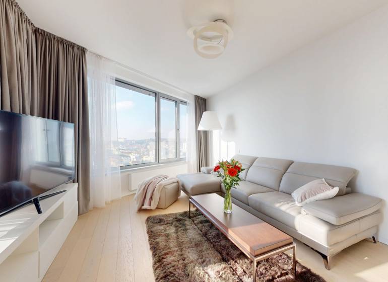 Elegantný byt na mieru s panorámou hradu  - Svetlá obývacia izba v 3-izbovom byte so sedačkou, stolíkom a televízorom.