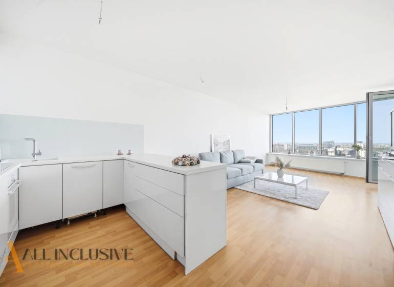 Na predaj luxusný 2-izb. byt s loggiou v Bratislave  - Svetlá kuchyňa s obývacou izbou, podlaha s dreveným dekorom, pohovka, veľké okná.