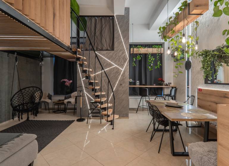 | Luxusný dvojúrovňový mezonet v Starom Meste - Podlaha s dreveným dekorom, schody, zelené rastliny a interiér 3-izbového bytu.