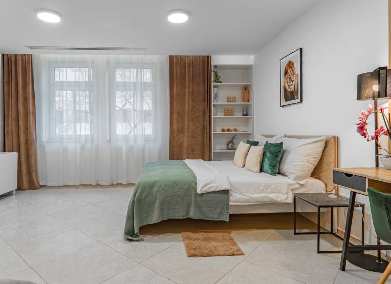 I Luxusný byt v historickom centre Bratislavy - Spálňa 2-izbového bytu s veľkou posteľou, pestrými doplnkami a nábytkom v svetlých tónoch.