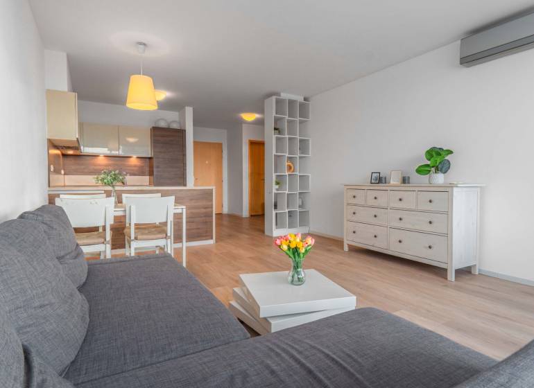 I na predaj 2i byt v komplexe Tri Veže na Bajkalskej - Obývačka s podlahou s dreveným dekorom a kuchynským kútom v 2-izbovom byte.