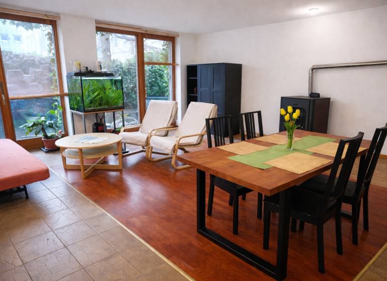 Prenájom 3-izbového bytu so záhradkou, 81m2, Pezinok-Centrum. - Obývacia izba v 3-izbovom byte s podlahou s dreveným dekorom, jedálenským stolom a akváriom.