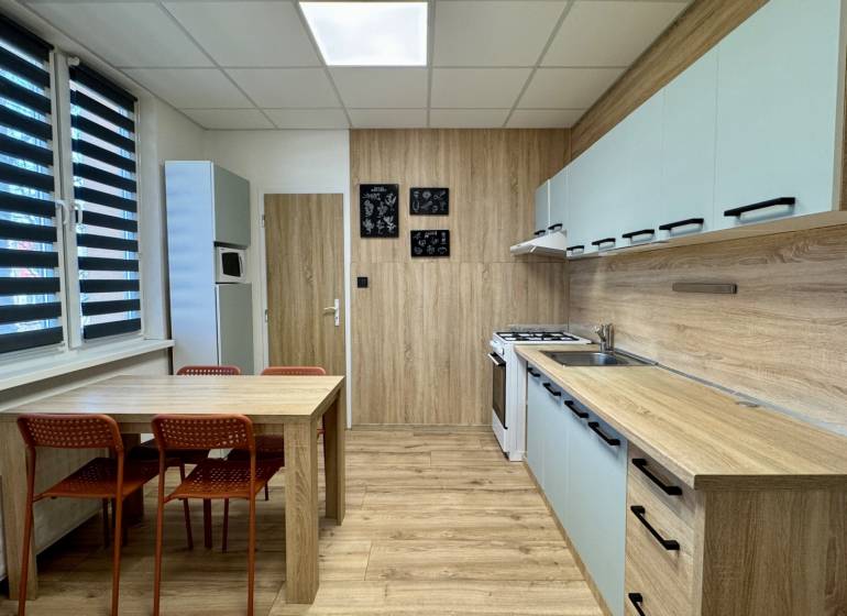 NA PRENÁJOM veľký 3 izbový byt na Čermáni NITRA - Kuchyňa v 3-izbovom byte s jedálenským stolom a podlahou s dreveným dekorom.