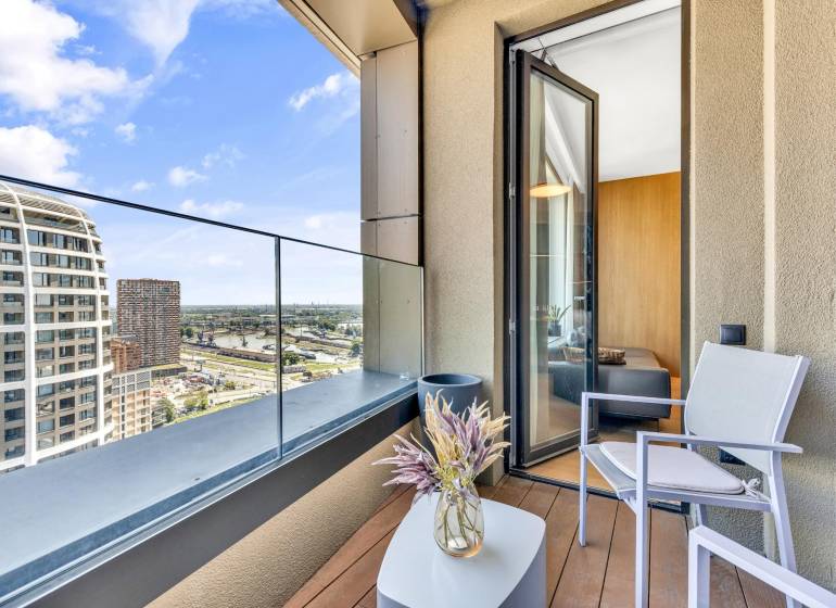 Predaj luxusný 2-izbový byt, 52 m2, Továrenská ul, SKY PARK - Balkón s výhľadom na mesto, konferenčný stolík, stolička a váza s rastlinou.