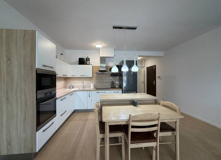 3-izbový byt s garážovým státím – Košice Západ, ul. Topoľčianska - Kuchyňa v 3-izbovom byte s podlahou s dreveným dekorom a jedálenským stolom.