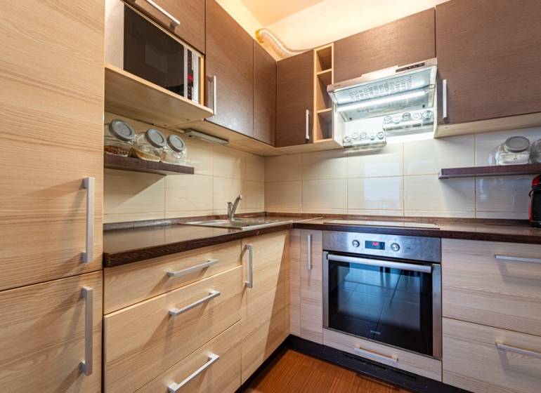 SVETLÝ ZARIADENÝ 2-IZBOVÝ BYT S BALKÓNOM - LA VITA  - Kuchyňa v 2-izbovom byte s podlahou s dreveným dekorom a vstavanými spotrebičmi.